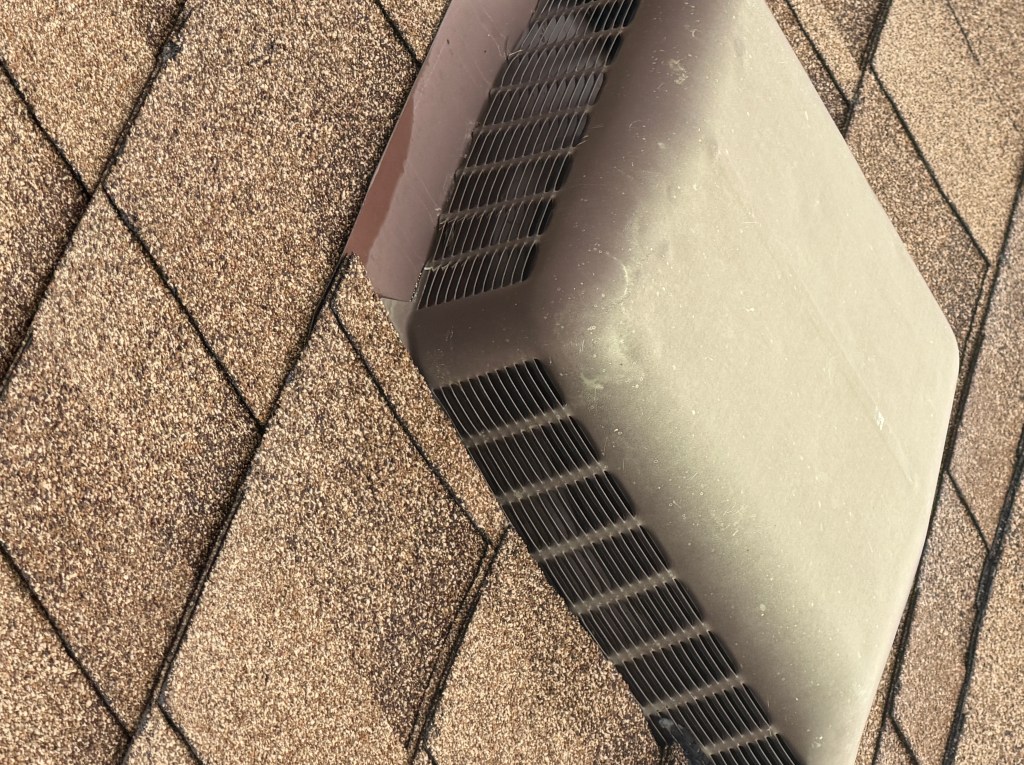 Hail impact dents on a metal roof vent during a Colorado roof inspection